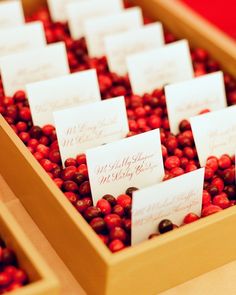 there are many red berries in the box with place cards on them for guests to write their names