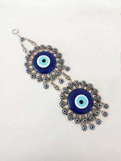 the evil eye earrings are made from glass beads and metal chains, with blue eyes on them