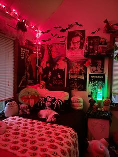 a bedroom decorated in pink and black with halloween decorations on the walls, bedding, and posters