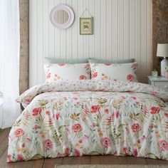 a bed with white and pink flowers on it in a room next to a window