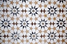 an intricately designed tile with black and white stars on it's sides, as well as brown dots in the middle