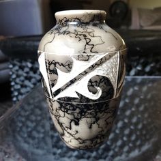 a black and white vase sitting on top of a glass table