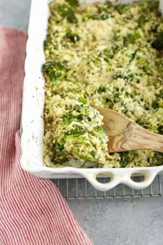 broccoli and rice casserole in a white dish with a wooden spoon