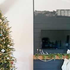 a decorated christmas tree in front of a fireplace with a flat screen tv on it