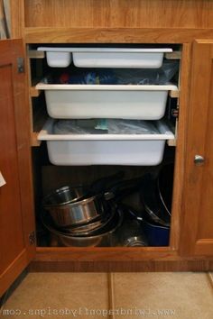 the kitchen cabinet is full of dishes and pans in it's bottom drawer