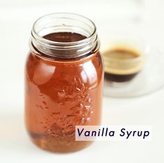 a glass jar filled with liquid sitting on top of a white table next to a spoon