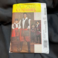 an old book with some pictures of men in costumes on top of black cloths