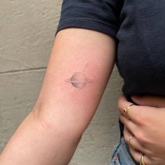 a woman with a small saturn tattoo on her arm