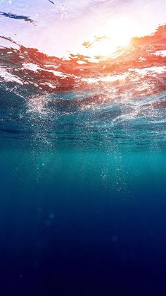 the sun shines brightly through the water as seen from under the ocean surface in this photo