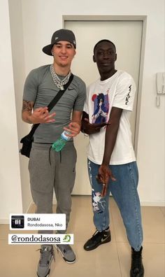 two young men standing next to each other in front of a wall with an open door