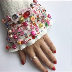 a woman's hand with red nail polish and white knitted gloves covered in colorful buttons