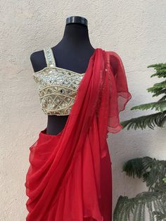 This radian red ruffled draped (pre-stitched) chiffon saree with ruffle detailing is paired with a mirror and pearl hand embroidered bustier blouse. Chiffon Blouse Piece For Navratri Party, Party Wear Pre-draped Georgette Saree With Gota Work, Party Pre-draped Saree With Gota Work In Georgette, Party Pre-draped Georgette Saree With Gota Work, Chiffon Ruffled Saree For Party, Red Chiffon Party Saree, Party Wear Chiffon Pre-draped Saree, Festive Chiffon Choli With Traditional Drape, Chiffon Pre-draped Saree With Mirror Work For Party