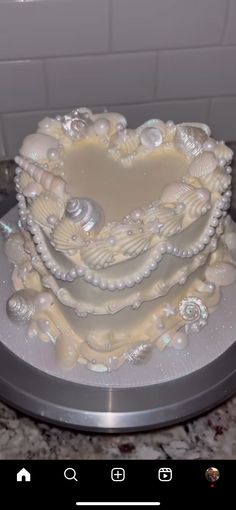 a heart shaped cake with seashells and pearls on it's sides, sitting on top of a counter