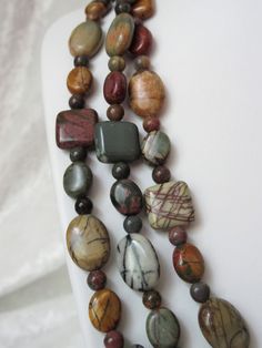 "This Red Creek jasper jewelry is a beautiful multi earth toned set. Red Creek jasper runs from browns, reds, tans, sage, and more with many interesting inclusions. There is a wide variety of beads, 14mm flat ovals flat ovals, 12mm flat squares, 8mm flat ovals and 4mm rounds. A large brass heart lobster clasp was used. This necklace is 60\" long and can be worn as 2 or 3 strands. The earrings dangle 1.25\" from the loop of the gold plated ear wire. This set will be mailed in a box." Handmade Brown Double Strand Jewelry, Unique Brown Jewelry With Natural Variations, Multi-strand Brown Jewelry With Gemstone Beads, Brown Multi-strand Jewelry With Gemstone Beads, Brown Jasper For Jewelry Making, Earthy Brown Multi-strand Jewelry, Earthy Jasper Hand-strung Jewelry, Multicolor Jasper Gemstone Beads Jewelry, Earthy Jasper Round Bead Jewelry