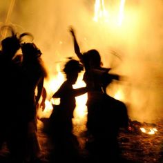 silhouettes of people dancing in front of a fire with bright yellow and orange lights