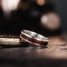 two wedding rings sitting on top of a wooden table next to an object in the background