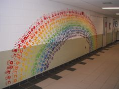 a rainbow painted on the side of a wall next to a hallway with hand prints