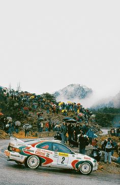 a car that is sitting on the side of a road in front of a crowd