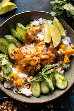 a bowl filled with rice, cucumbers and sauce next to sliced limes