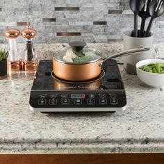 a stove top with a pot on it and some utensils in the background