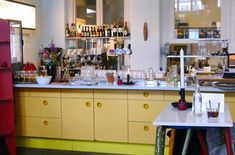 a kitchen filled with lots of bottles and glasses on top of a counter next to a red refrigerator