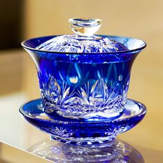 a blue glass bowl and saucer sitting on top of a table