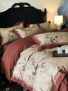 a bed with red and tan comforters in a bedroom next to a night stand