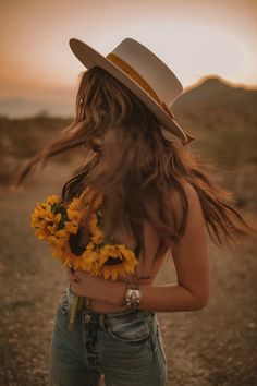 a woman with sunflowers in her hand and hat on top of her head