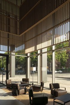 an empty lobby with couches, tables and lamps on the side walk in front of large windows