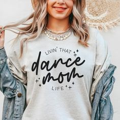 Dance mamas, we made the perfect shirt for watching your little dancer in class, dress rehearsal or a performance! Our dance mom life tee is available in pink and ash, and is soooo cute to match our dance your heart out tee for the littles! This design is also available in a match tote bag to carry around dance shoes, extra water, snacks and maybe a hairbrush for those ballet buns?? DETAILS Unisex sizing - aka mens sizing. If you want a looser fit, we recommend ordering your normal size or one up for an oversized fit. If you prefer a more fitted style, size down one. Tee - 52/48 Airlume combed and ringspun cotton/polyester. Side seams, shoulder to shoulder taping, tearaway label. Pink or Ash tee with black print Dance Aunt Shirt Ideas, Dance Mom Shirts Design, Dance Studio Merch, Dance Mom Tshirt Ideas, Dance Mom Outfits, Dance Mom Shirt Ideas, Ballet Buns, Dance Shirts Ideas, Dance Moms Outfits