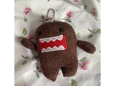 a brown stuffed animal with a red mouth and teeth on it's back laying on a white sheet