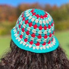 a woman wearing a crocheted hat with red, white and blue flowers on it