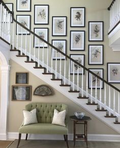 a green chair sitting under a staircase next to a set of pictures on the wall