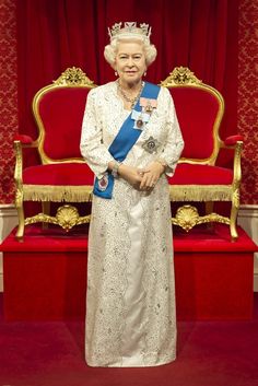 the queen of england is standing in front of a red chair