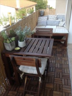 a wooden table sitting on top of a patio next to a white couch and potted plants