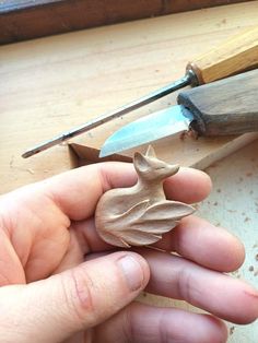 a person holding a small wooden object in their hand next to a pair of scissors