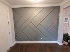 an empty room with wood floors and gray wallpaper on the walls, in front of a white door