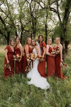 a bride and her bridals posing for a photo in the grass with their bouquets