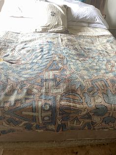 a bed with an intricately designed comforter on it's headboard and foot board