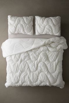 an unmade bed with white sheets and pillows