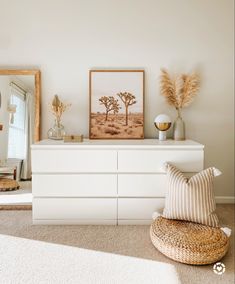 a white dresser sitting in a bedroom next to a mirror and vase on top of it