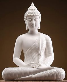 a white buddha statue sitting on top of a wooden table