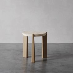 a small wooden table sitting on top of a cement floor next to a white wall