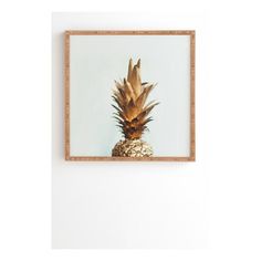 a pineapple is hanging on the wall in front of a white wall with a wooden frame