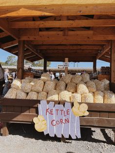 there is a sign that says kettle the corn under a covered area with people standing around it