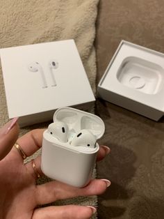 a person holding an apple airpods in their hand next to the box that is open