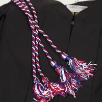 a black graduation gown with red, white and blue tassels