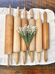 a bunch of wooden rolling pins sitting on top of a white cloth next to some flowers