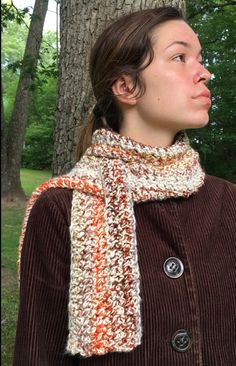 a woman standing next to a tree wearing a scarf