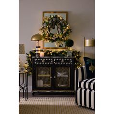 a living room decorated for christmas with black and white striped furniture, gold accents and a wreath on the wall